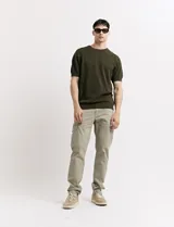 Pantalón de gabardina color marrón, corte slim fit, con bolsillos laterales tipo cargo.