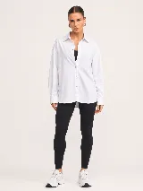 Camisa blanca de popelina oversize con cuello clásico, cierre frontal de botones y mangas largas con puños.