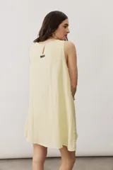 Vestido corto blanco sin mangas, con cuello redondo y detalle de nudo drapeado en el lateral.