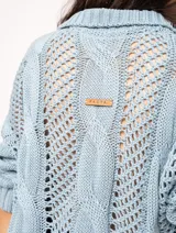 Sweater tejido de algodón color crudo, con cuello polo y escote en V. Diseño con ochos verticales en delantera, espalda y mangas, y punto abierto.