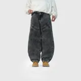Pantalón jean de corte ultra baggy, color negro con efecto lavado ácido. Presenta costuras curvas decorativas en la parte superior y diseño de piernas amplias con ajuste en los tobillos.