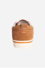 Zapatilla casual de cuero color camel, estilo skate o lona, con cordones marrones y suela de goma blanca con una línea naranja decorativa.