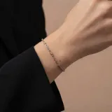 Pulsera de cadena fina con eslabones de plata intercalados con pequeños detalles en oro, diseño minimalista y elegante.