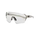 Lentes deportivos de diseño envolvente con marco gris translúcido y lentes fotocromáticos transparentes con patrón de puntos sutiles. Incluyen almohadillas nasales ajustables para mayor confort.