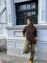 Buzo unisex de tejido de punto grueso en lana merino, color rojo, con cuello redondo y diseño de calce relajado. Presenta un detalle bordado a mano en contraste en la manga.