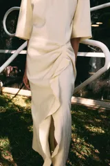 Vestido midi de Zara Woman Collection, confeccionado en mezcla de viscosa, con cuello redondo, manga corta y detalle de drapeado lateral con volado. Presenta bajo asimétrico y cierre en la espalda.