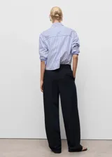 Pantalón de vestir de tiro bajo y diseño wide leg color azul marino, con pinzas en la parte delantera y bolsillos laterales.