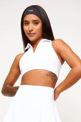 Top deportivo blanco con diseño de cuello polo y escote en V, confeccionado en tejido técnico de alto rendimiento con protección UV50+.