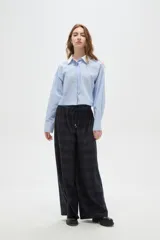 Pantalon de corte ancho y tiro alto, confeccionado en tela con estampado a cuadros en tonos verdes. Presenta cintura elástica con cordón de ajuste frontal.