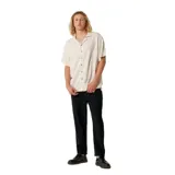 Camisa de manga corta color beige claro, con cuello cubano y botones frontales marrones. Presenta una textura sutilmente tejida.