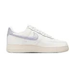 Championes Nike Air Force 1 de corte bajo, con cuerpo de cuero blanco, suela de goma color crema y detalles en tono lila metalizado en el swoosh lateral y el talón.