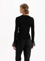 Top de tejido de punto fino color negro, con ajuste al cuerpo, cuello redondo y mangas largas que terminan en puños acampanados con detalle de tejido calado.