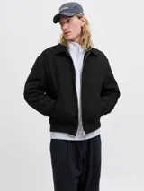 Campera bomber negra con cuello camisero, cierre frontal completo y bolsillos laterales, con puños y dobladillo acanalados.
