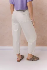 Jeans de tiro alto y silueta barrel, color crudo, con cinco bolsillos, presillas para cinturón y cierre frontal con botón y cremallera. Presenta diseño de pierna amplia con leve entalle hacia el ruedo y dobladillo vuelto.