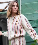 Cárdigan blanco de lana merino tejido en punto jersey, con diseño de rayas verticales bordadas a mano en tonos pasteles en el frente y las mangas. Cuenta con cuello redondo y cierre frontal con botones al tono.