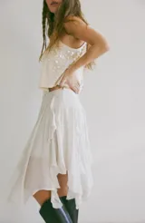 Pollera midi blanca de viscosa con volados irregulares en capas. Se ajusta a la cintura con un cinturón negro con hebilla metálica.