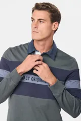 Polo de manga larga con cuello clásico y tapeta de botones. Diseño a rayas horizontales en tonos de gris y azul.