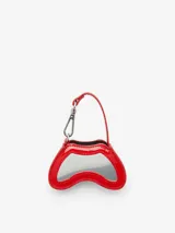 Minibolso charm Diesel Play con diseño inspirado en un control de videojuegos, confeccionado en material de acabado brillante color rojo. Presenta el icónico logo metálico Oval D en el frente y un gancho superior tipo llavero con correa.