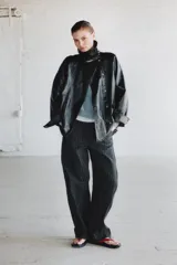 Chaqueta de cuello alto y manga larga con acabado brillante efecto cuero. Presenta cierre frontal con cremallera y botones a presión, bolsillos delanteros y puños definidos.