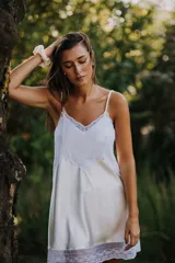 Camisón corto de satén color crema con detalles de puntilla gris en el escote y en el ruedo. Presenta breteles finos ajustables y un diseño fluido.