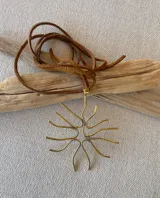 Colgante con dije de bronce con forma de coral y cordón de cuero marrón.