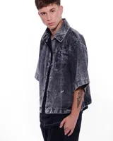 Camisa de denim negra con efecto lavado, corte recto, mangas cortas y bolsillo en el pecho.