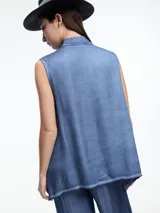 Camisa sin mangas color beige claro con efecto teñido en frío y aspecto gastado. Presenta cuello clásico, cartera oculta y ruedo irregular, más largo en los laterales.