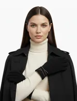 Guantes negros de tejido suave (soft), con detalle de tiras cruzadas en tono beige o dorado claro en la muñeca.