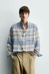 Camisa de corte relajado confeccionada en tejido ligero de algodón, con diseño de cuadros en tonos azules y beige. Presenta cuello solapa, cierre frontal de botones, manga larga con puño abotonado y un bolsillo en el pecho.