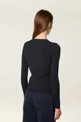 Sweater de punto fino en color negro, con diseño de canalé, cuello redondo y mangas largas. Presenta un corte ajustado con aberturas laterales en el ruedo y está decorado con pequeñas cuentas doradas en la parte frontal.