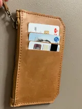 Billetera tarjetero de cuero con cierre y espacio para billetes y monedas.