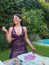 Vestido corto negro con estampado de plumas doradas, escote en V, breteles finos cruzados en la espalda, cut-outs laterales y volado en el ruedo.