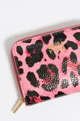 Billetera pequeña con cierre de cremallera, exterior con estampado de leopardo en tonos rosa y negro brillante, y logo metálico de Bimba y Lola en color dorado.