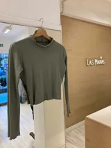 Remera de morley color mostaza, de manga larga, con cuello alto fruncido y terminaciones fruncidas en las mangas.