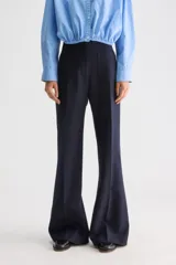 Pantalón azul marino de tiro alto y calce ajustado con diseño acampanado. Presenta bolsillos aplicados en el delantero y cierre frontal.