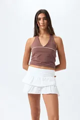 Top halter negro con escote en V y detalle de vivo blanco horizontal. Presenta un diseño ajustado al cuerpo y espalda descubierta con tiras regulables.
