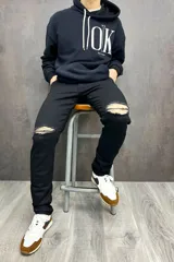 Pantalón de jean negro con roturas en las rodillas.