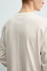 Camiseta de manga larga con corte relajado, confeccionada en tejido de algodón compacto. Presenta cuello redondo y detalle de costura en el centro de la espalda.