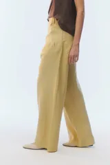 Pantalón de lino color tostado, de tiro alto y corte amplio con perneras rectas. Cuenta con pasacintos, bolsillos laterales y bolsillos traseros con solapa.