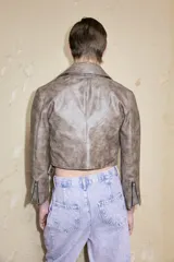 Chaqueta corta de cuero sintético color marrón con cierre cruzado y cuello con solapas.