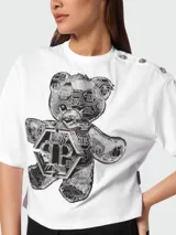 Camiseta corta blanca de algodón con cuello redondo y mangas cortas. Presenta un estampado frontal de un oso de peluche con strass y el logo de la marca Philipp Plein.