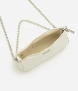 Cartera tipo baguette pequeña Satinato, confeccionada en PU color marfil, de formato alargado y estructura maleable. Cuenta con cierre superior de cremallera, placa frontal aplicada con el logo de la marca y asa de cadena doble metálica en tono plateado que permite llevarla al hombro o cruzada.