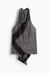 Top halter negro con estampado de lunares blancos, escote drapeado y espalda abierta con tiras anchas para anudar en la parte baja.