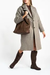 Tapado largo de corte oversize en color beige, con solapas clásicas y cierre frontal con botones. Presenta un diseño minimalista y elegante, ideal para un look sofisticado.