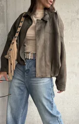 Campera tipo bomber de gamuza color verde, con diseño oversize, cuello camisero, cierre frontal y detalles de charreteras en los hombros.