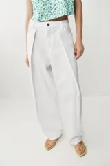 Jeans blancos de tiro medio y pernera ancha con corte barrel que se estrecha hacia el tobillo. Presenta cinco bolsillos, pliegues delanteros y cierre frontal con cremallera y botón metálico.