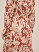 Vestido largo estilo camisero confeccionado en seda viscosa con estampado abstracto en blanco y negro. Cuenta con botones nacarados, bolsillos laterales, lazo para ajustar en la cintura y aberturas laterales.
