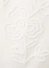 Jeans blancos de tiro medio con diseño wide leg y bordado de flores tono sobre tono en las perneras. Cuentan con diseño clásico de cinco bolsillos, trabillas y cierre frontal de botón y cremallera.
