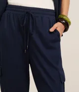 Pantalón largo verde militar de corte fluido, con cintura elástica, cordón de ajuste y bolsillos cargo en los laterales.