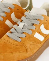 Championes deportivos Coolway modelo Goal, color naranja óxido con detalles en blanco, marrón y verde. Confeccionados en serraje suave con lengüeta preformada de piel, forro interior en piel, cordones planos de algodón bicolor intercambiables y suela flexible de goma y caucho.